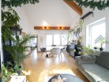 lichtdurchflutetes Wohnzimmer mit hoher Decke und Zugang zum Balkon